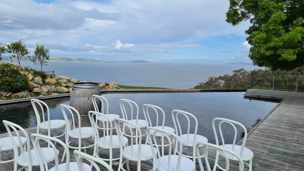 white plastic chairs near body of water during daytime