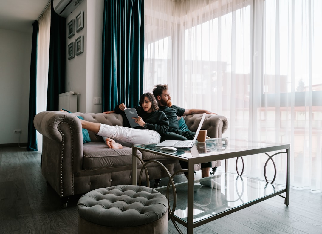 2 women sitting on sofa near window