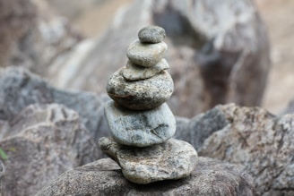 A serene rock cairn balanced on a smooth stone surface with a soft earth-toned background.