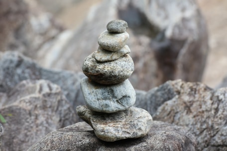 A serene rock cairn balanced on a smooth stone surface with a soft earth-toned background.