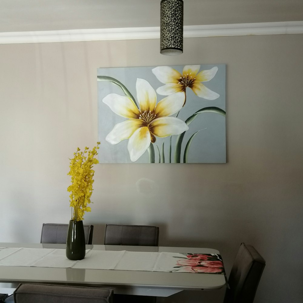 white and yellow flower in black vase on white table