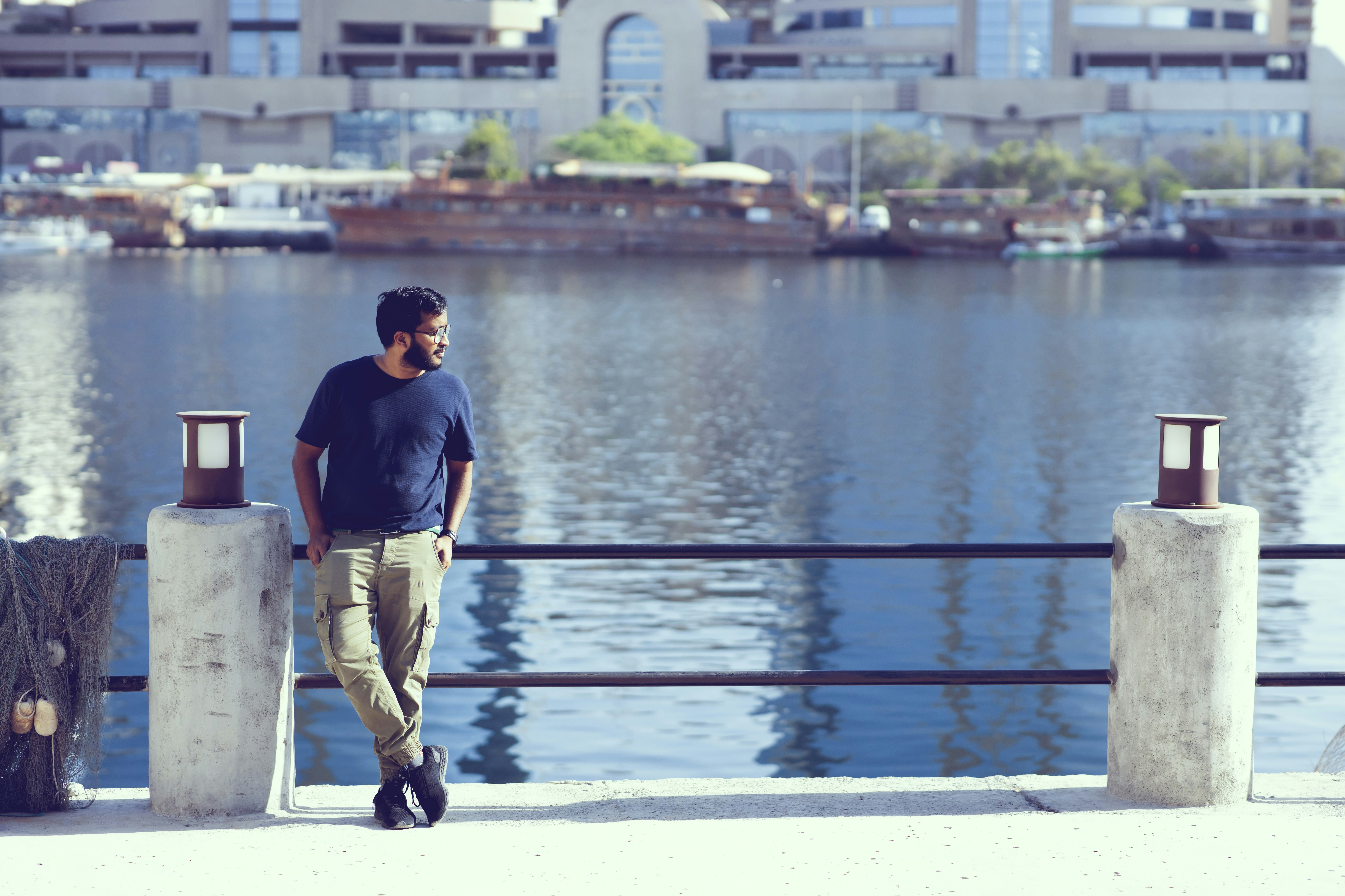 man in black crew neck t-shirt and brown pants standing beside body of water during