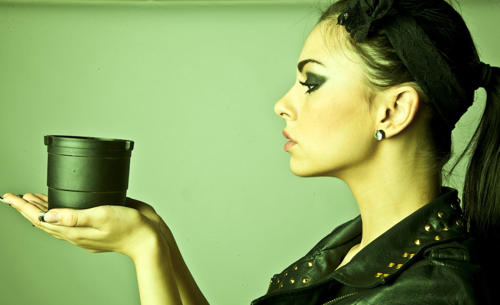 woman in black and white floral dress holding black ceramic mug