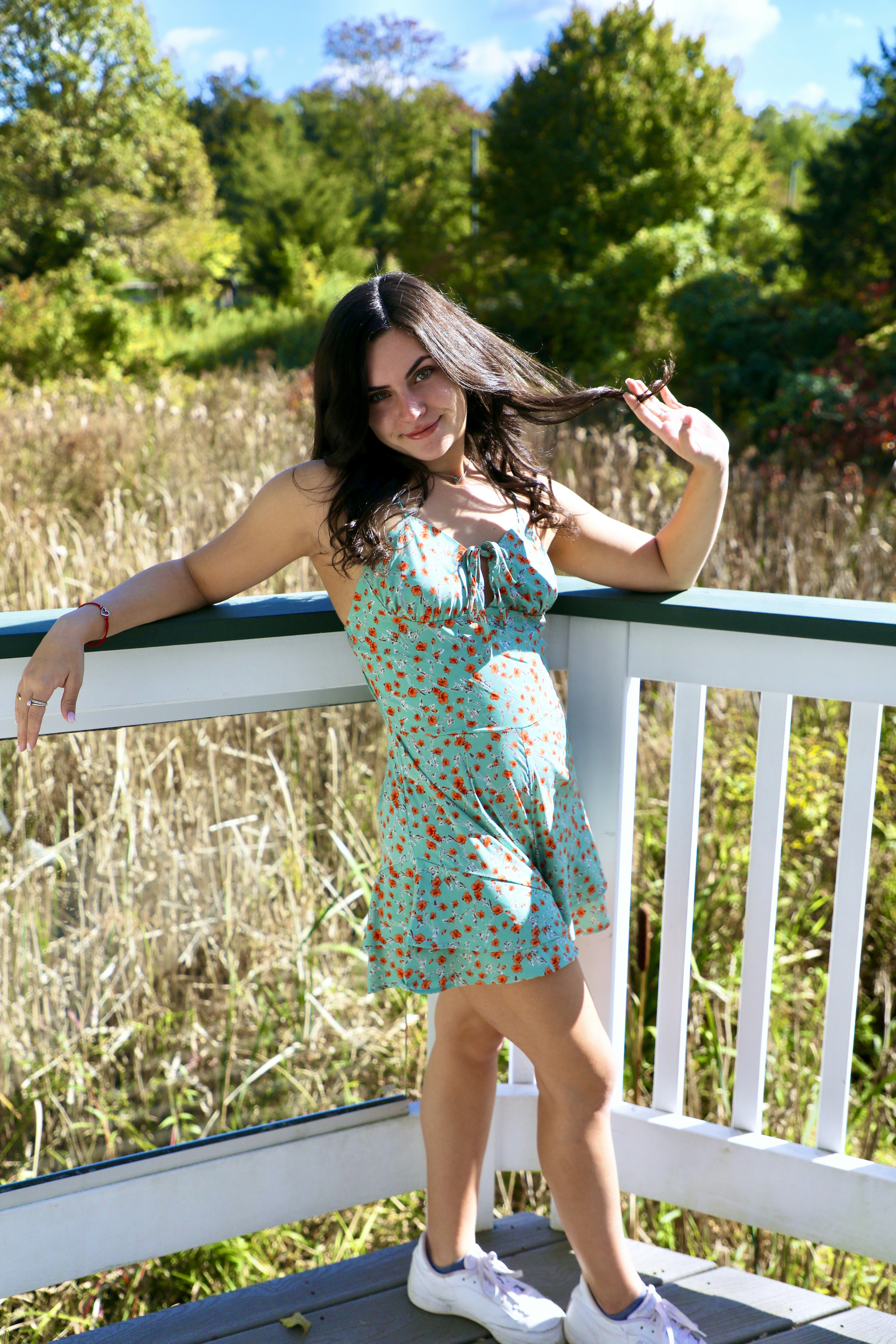 woman in white red and blue floral dress standing on brown grass field during daytime