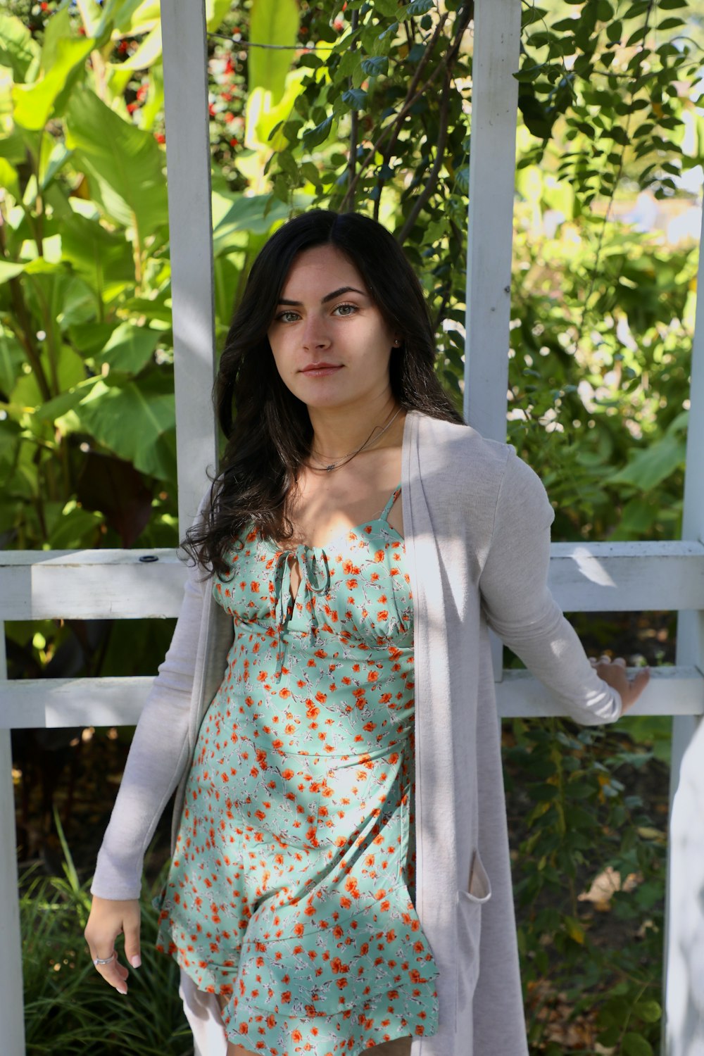 woman in white cardigan standing near green leaf plant during daytime