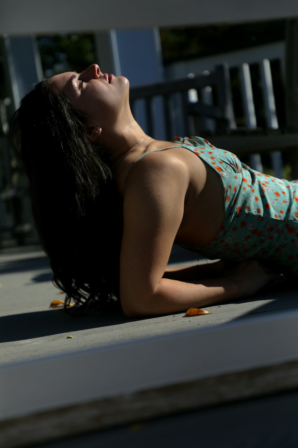 woman in blue and red floral spaghetti strap top lying on gray concrete floor during daytime