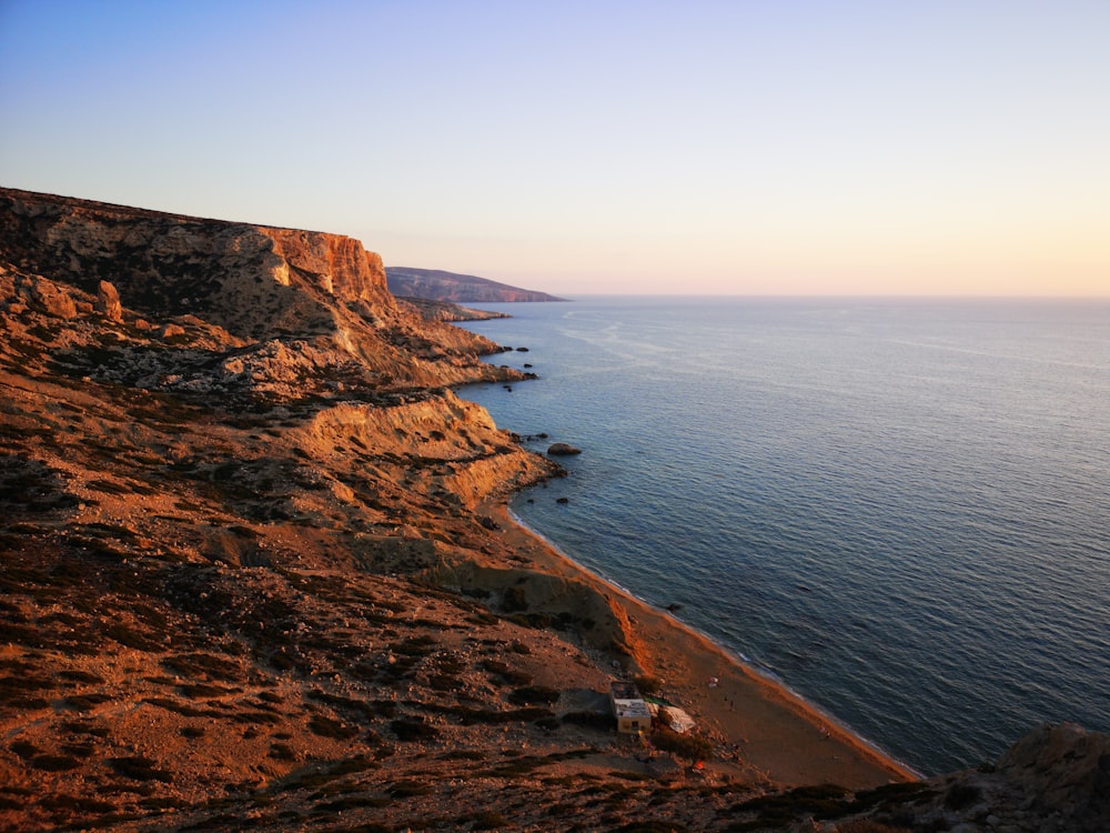 brown rock formation beside body of water during daytime