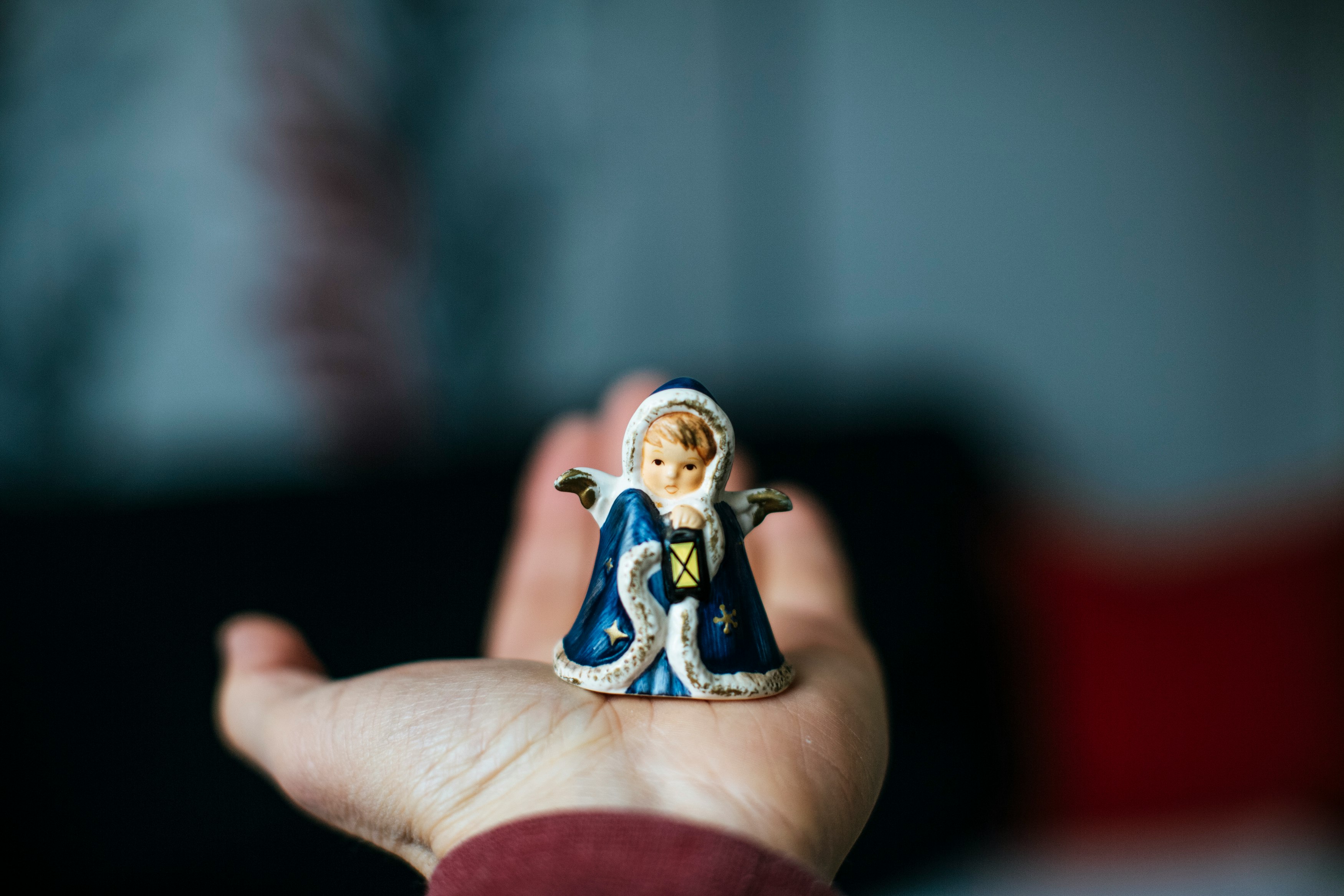 person holding white and blue ceramic figurine