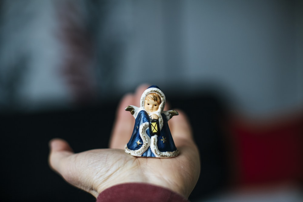 person holding white and blue ceramic figurine