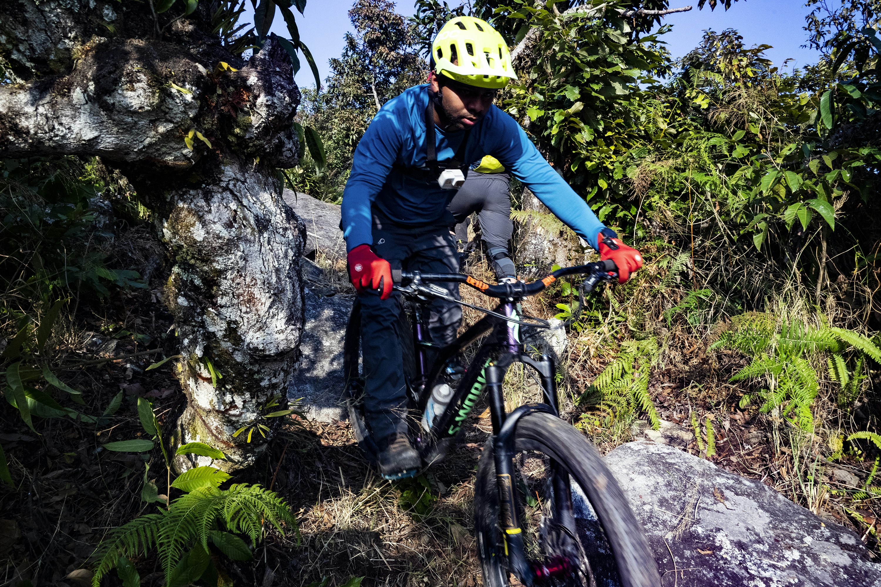 man in blue jacket and blue denim jeans holding black and orange mountain bike