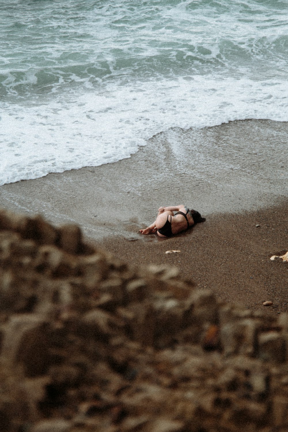 woman lying on beach shore during daytime