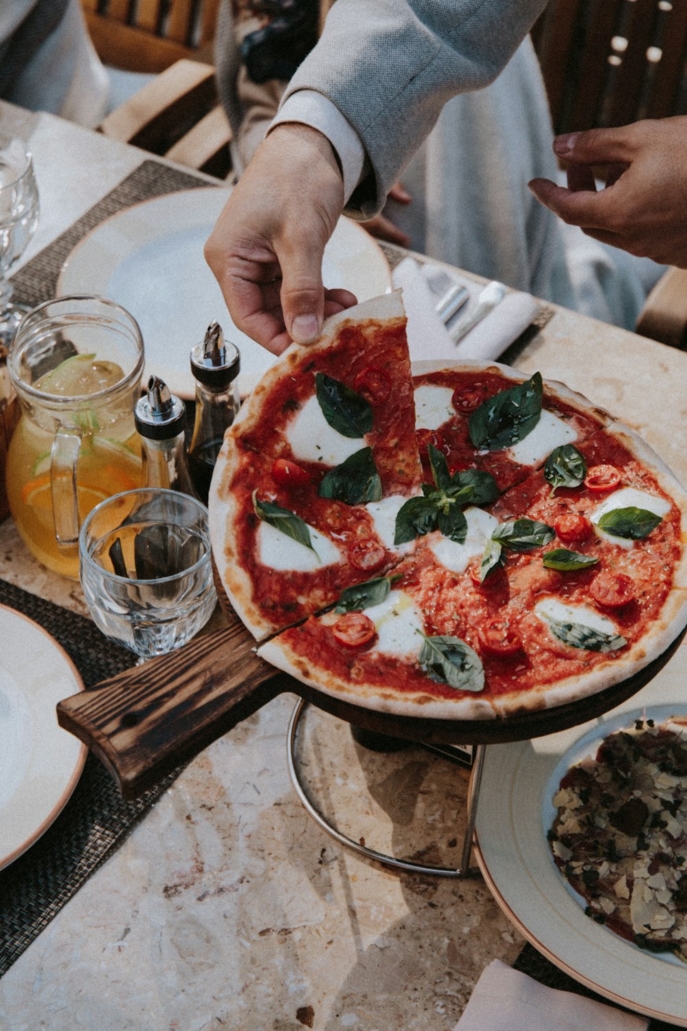 person holding pizza with tomato and basil