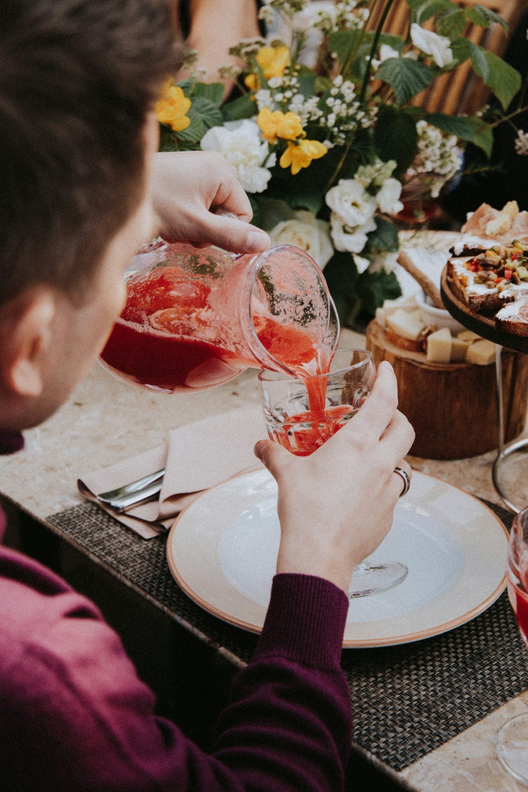 woman pouring red wine on clear drinking glass