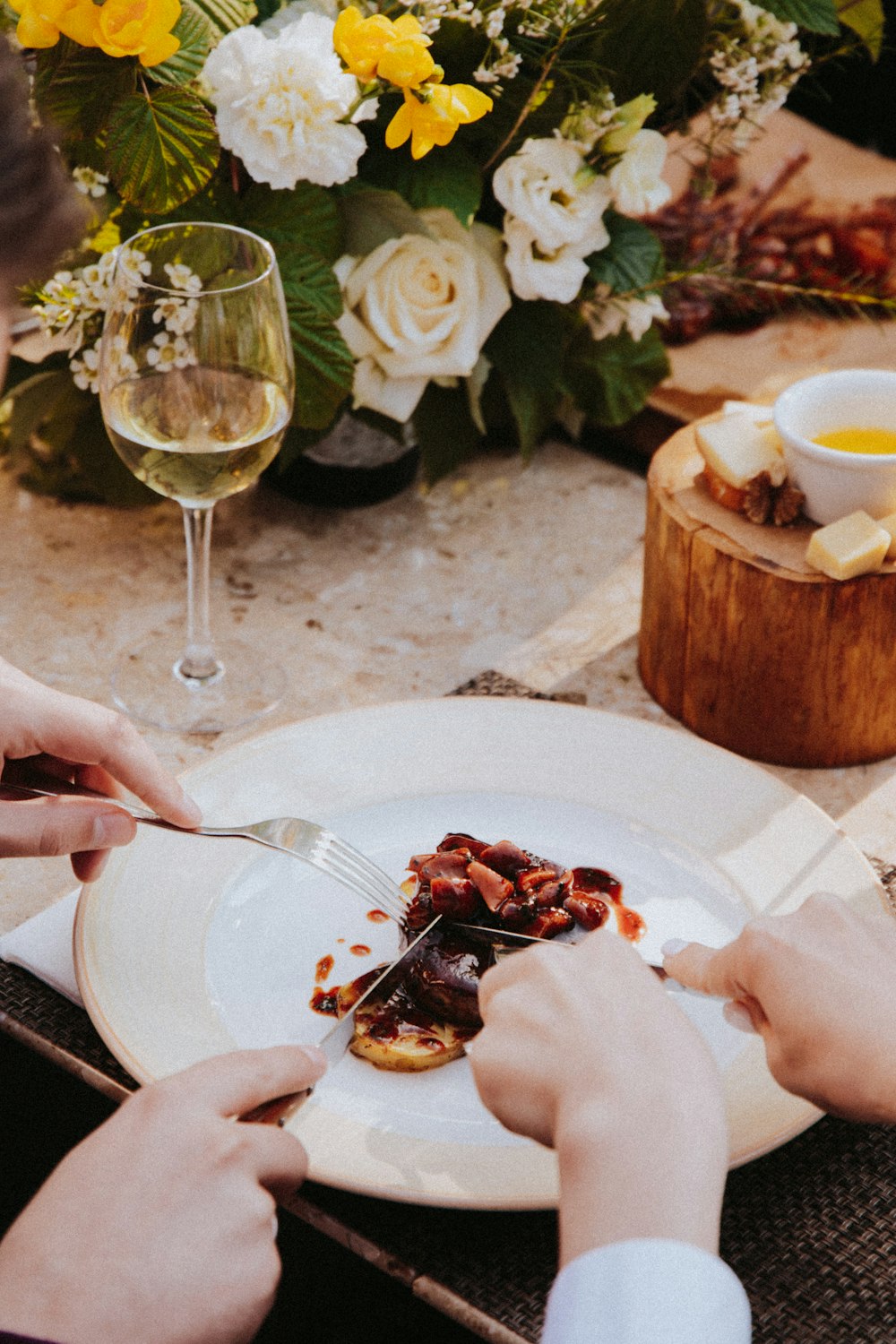 person holding stainless steel fork and knife slicing cooked food on white ceramic plate