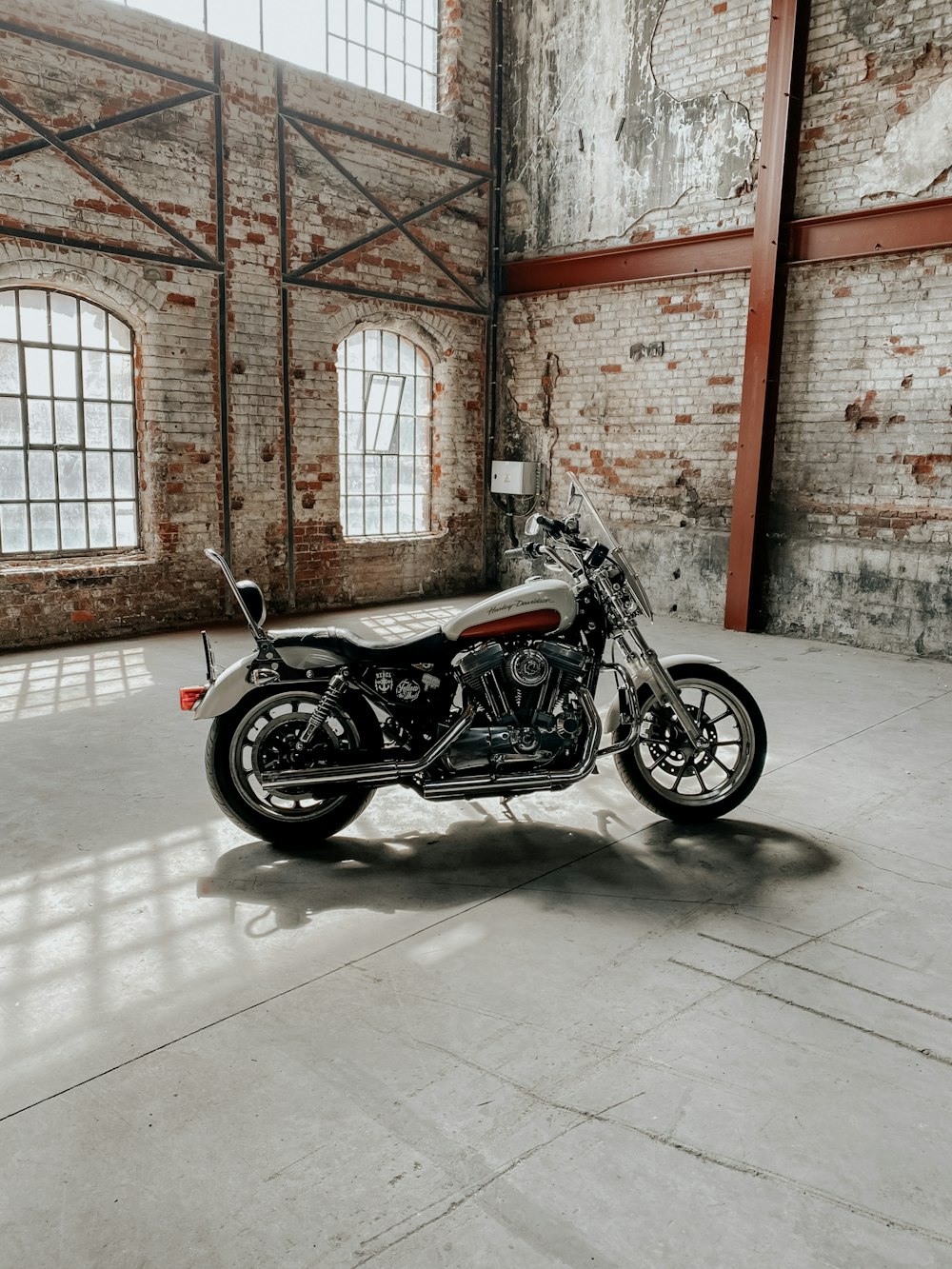 black cruiser motorcycle parked beside brown brick wall