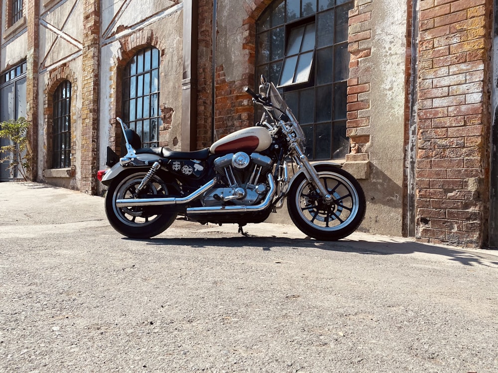 blue and black standard motorcycle parked beside brown brick wall