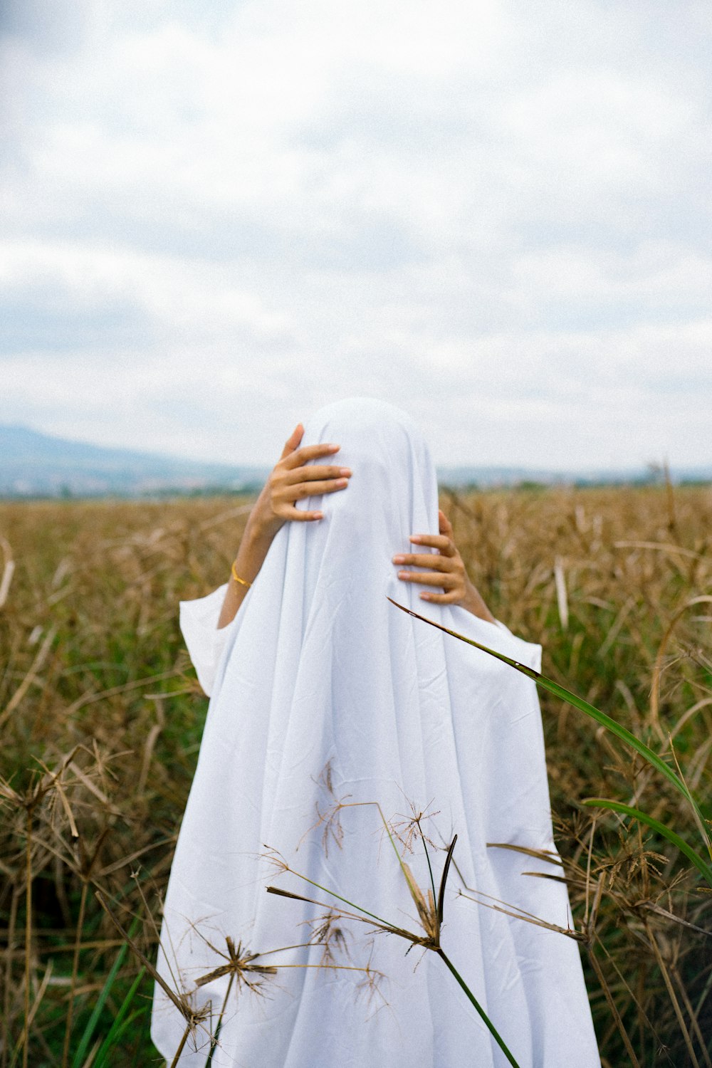 woman in white hijab standing on green grass field during daytime