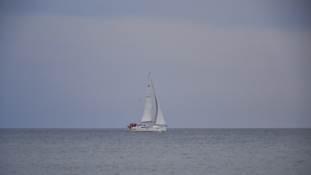 white sailboat on sea under white sky during daytime