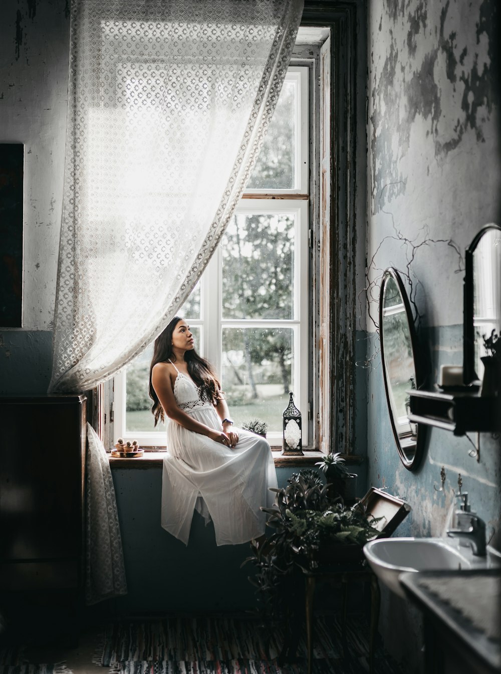 woman in white dress standing in front of window