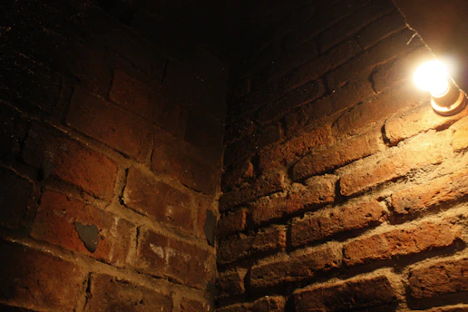 A gritty, dark concrete wall textured with subtle film grain, illuminated by a single streak of empire gold light.