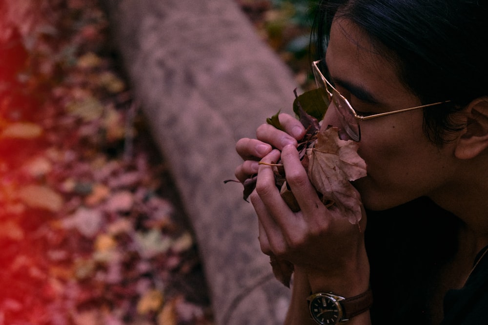 woman in black framed sunglasses holding brown dried leaves