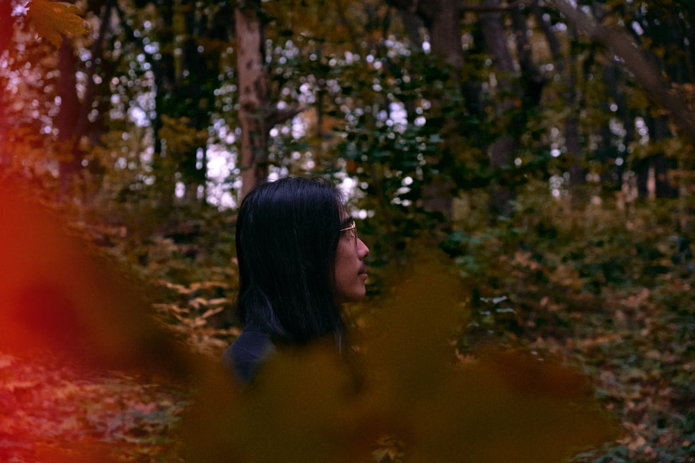 woman in black long sleeve shirt standing near green trees during daytime