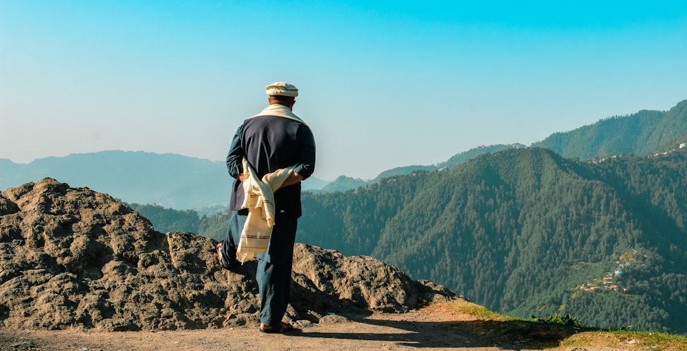 man in black jacket standing on rock mountain during daytime