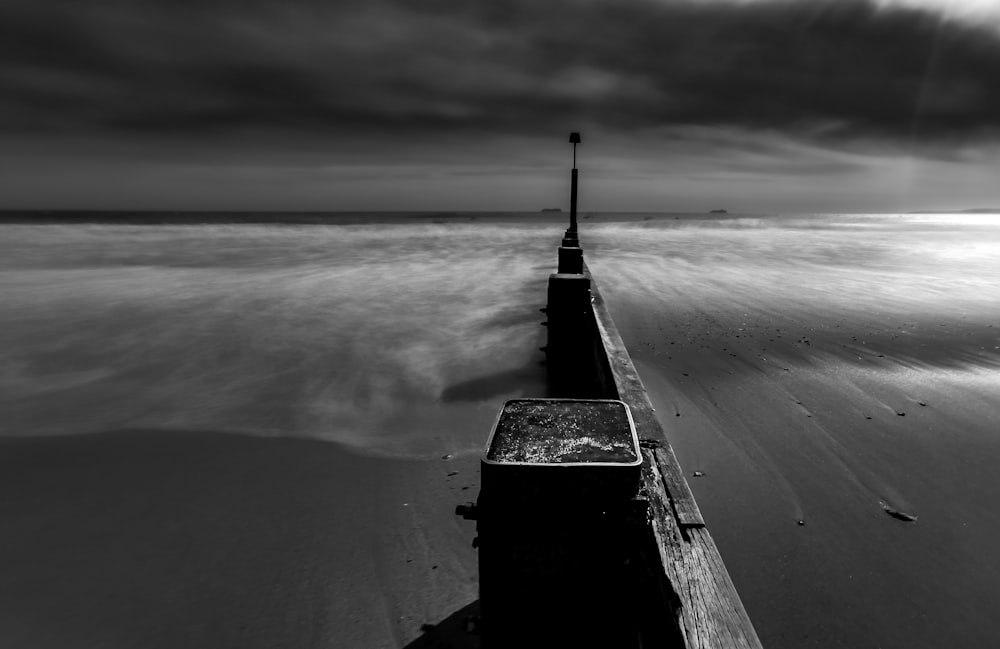 grayscale photo of wooden dock on beach