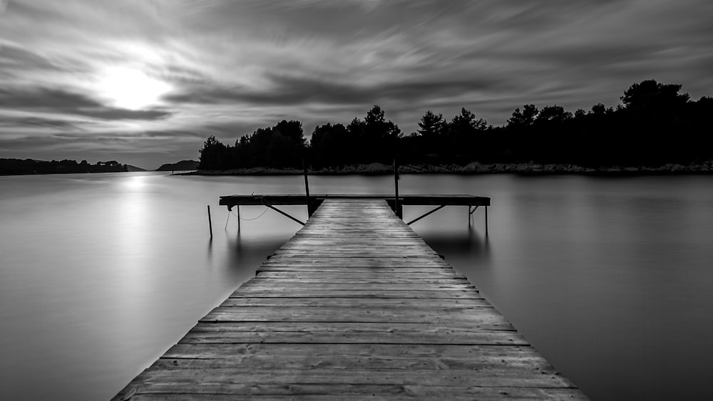 grayscale photo of wooden dock on lake