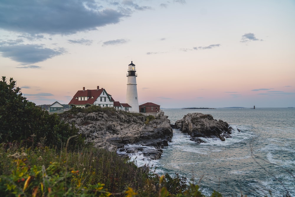 farol branco e preto na costa rochosa marrom durante o dia