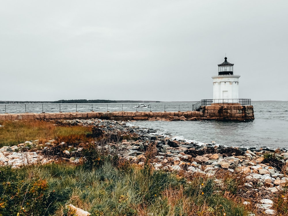 white and black lighthouse near body of water during daytime