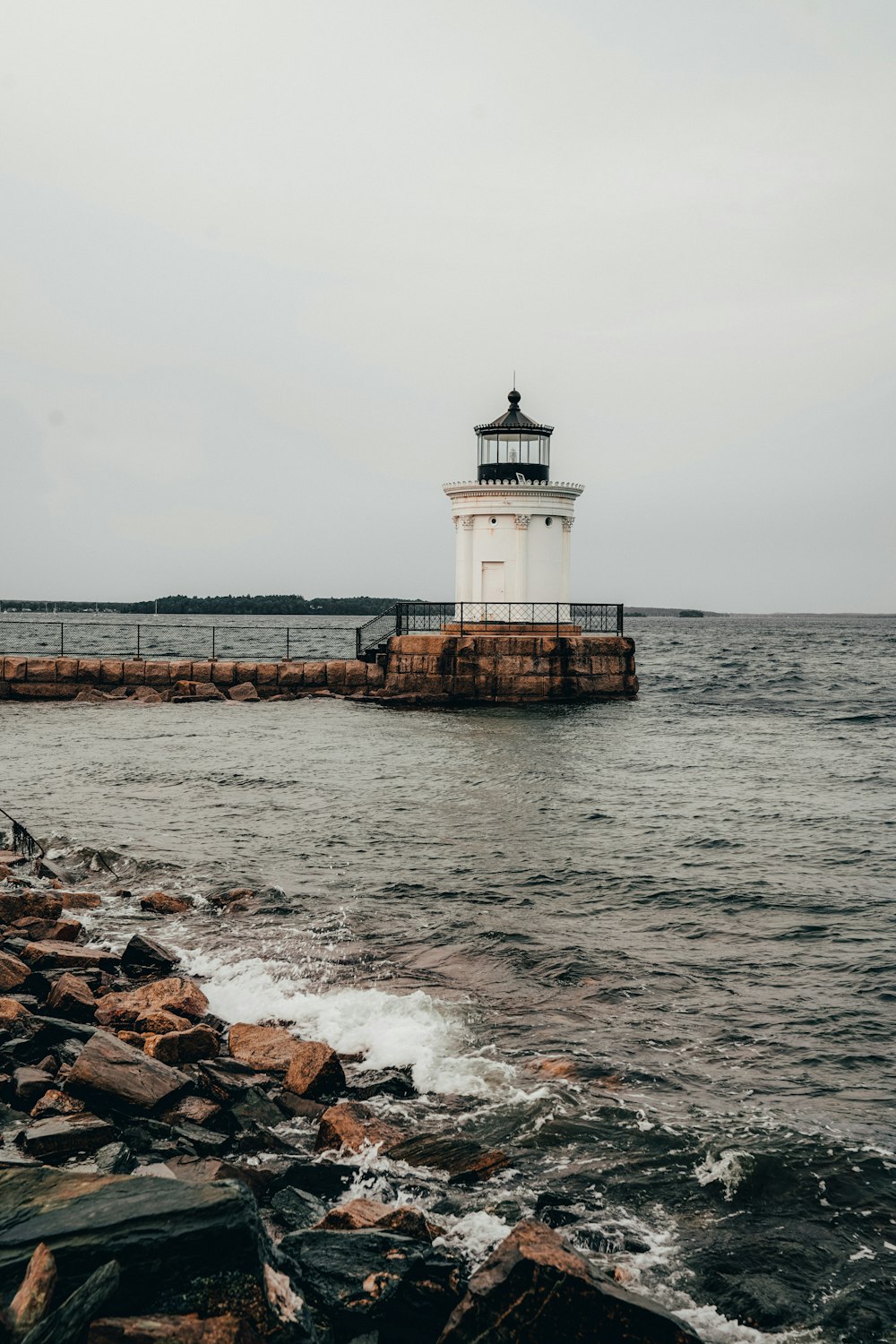 white lighthouse on brown rocky shore during daytime