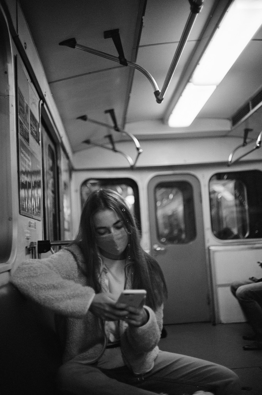 grayscale photo of woman in long sleeve shirt sitting on train