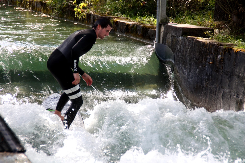 Hombre con traje de neopreno blanco y negro sobre el agua durante el día