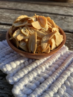 Close-up of vibrant dehydrated garlic flakes spilling from a rustic wooden bowl