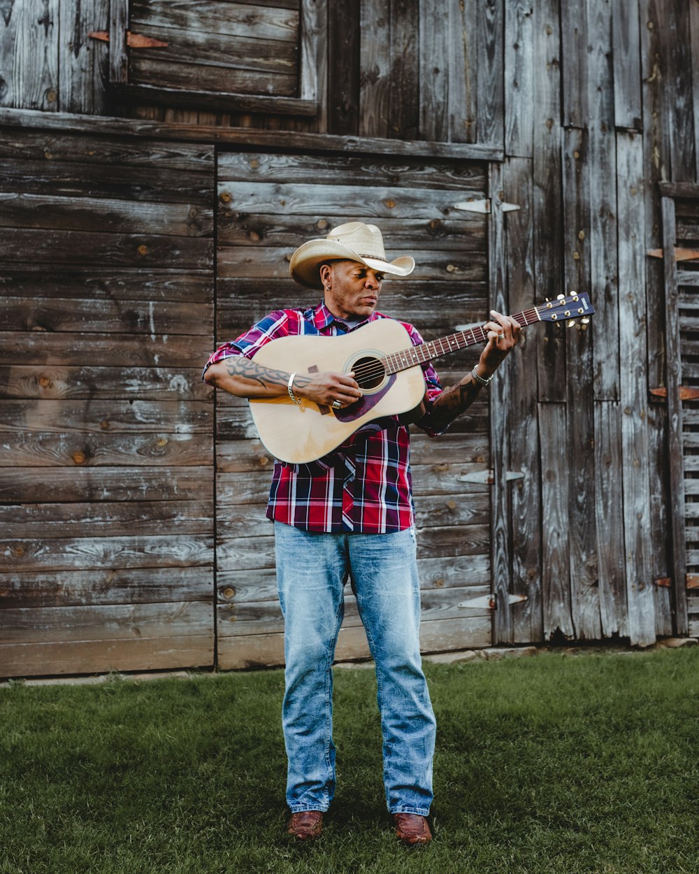 man in brown cowboy hat playing acoustic guitar