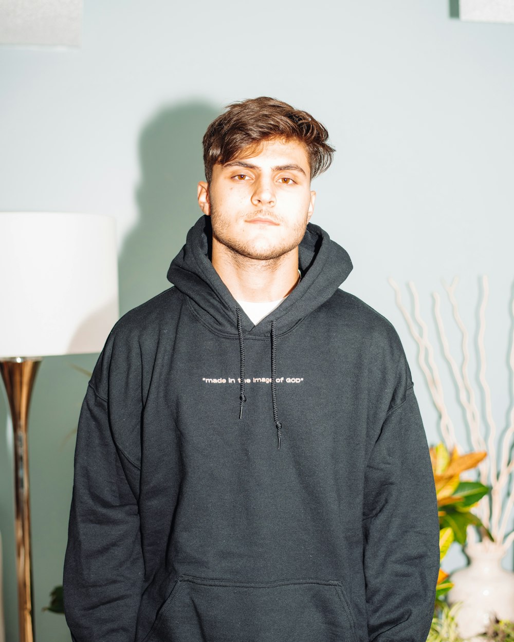 man in gray hoodie standing near white wall