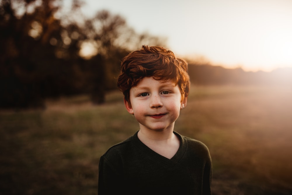 boy in black crew neck shirt standing on green grass field during daytime