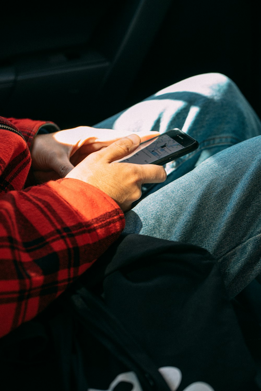 person in red and black plaid long sleeve shirt holding black smartphone