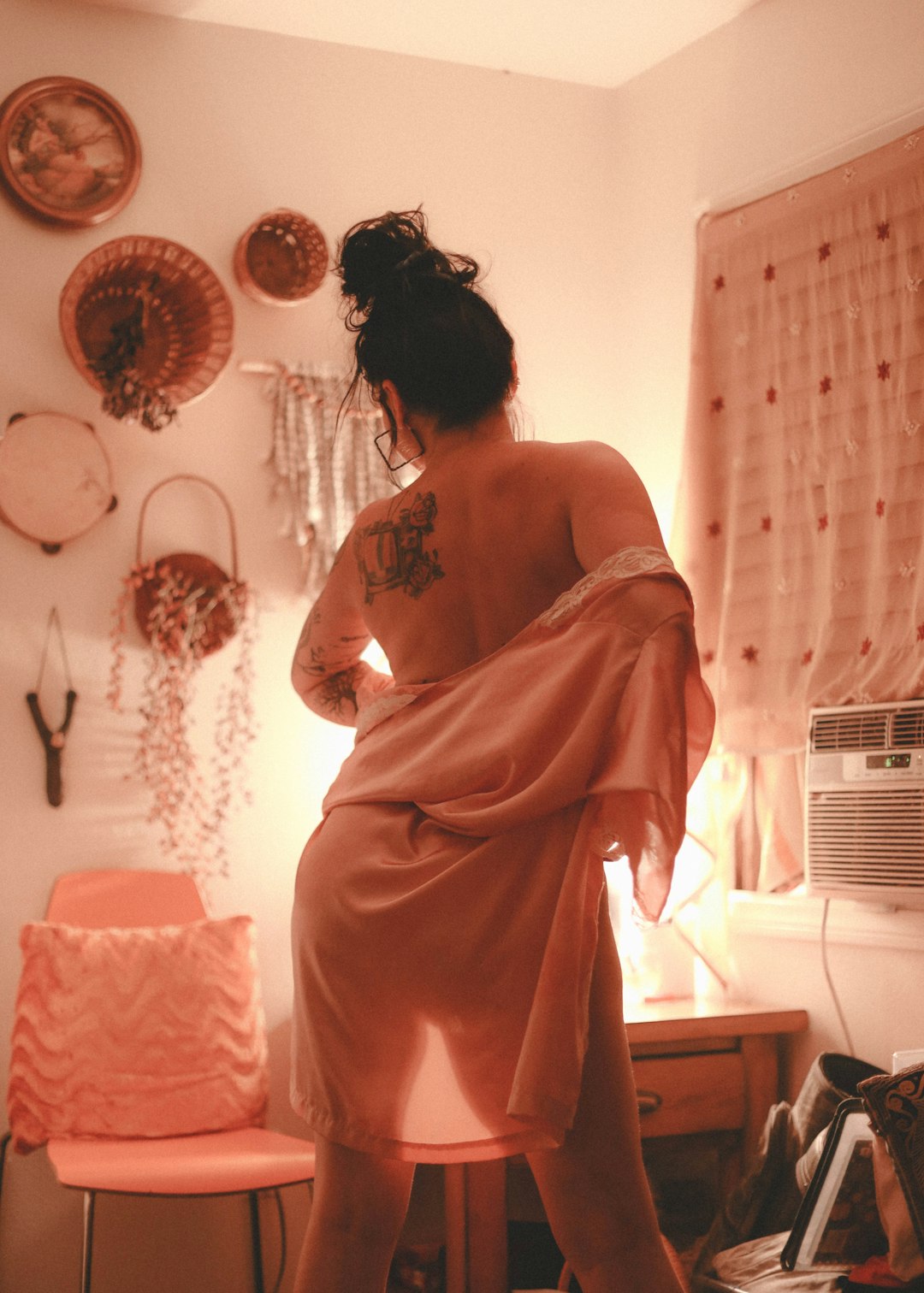 woman in orange dress standing near window