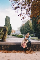 A candid photo of a couple laughing together on a park bench under autumn leaves.