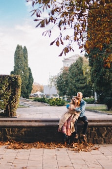 A cozy couple sitting together on a park bench during autumn.