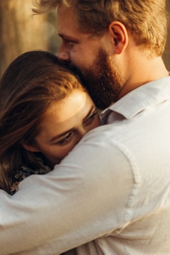 A close-up of two people embracing, with one person resting their head on the other's shoulder. The lighting is warm, creating a cozy and intimate atmosphere.