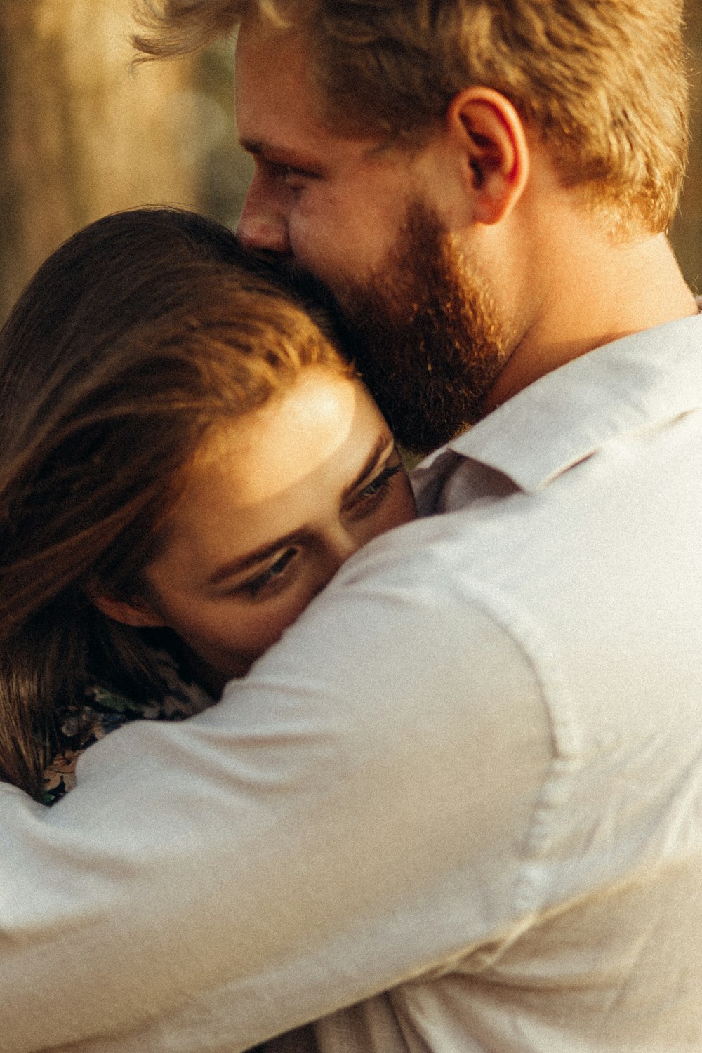 man in white dress shirt kissing woman in black hair