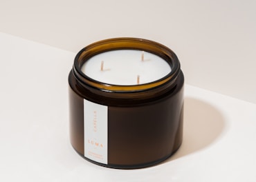 Elegant white candles in glass jars with minimalist labels.