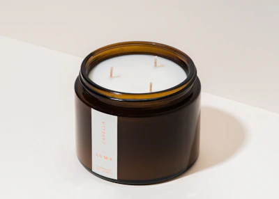 Elegant white candles in glass jars with minimalist labels.