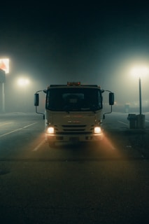 Tow truck headlights cutting through fog on a quiet Platteville road at night.