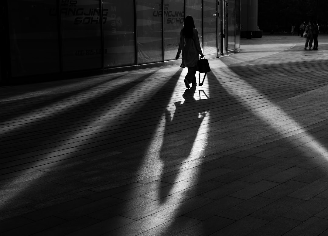 grayscale photo of woman walking on hallway