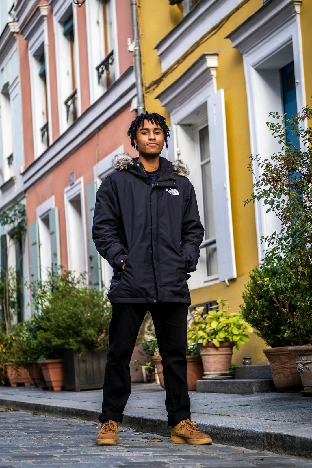  man in black zip up jacket standing near green plant during daytime coat stand