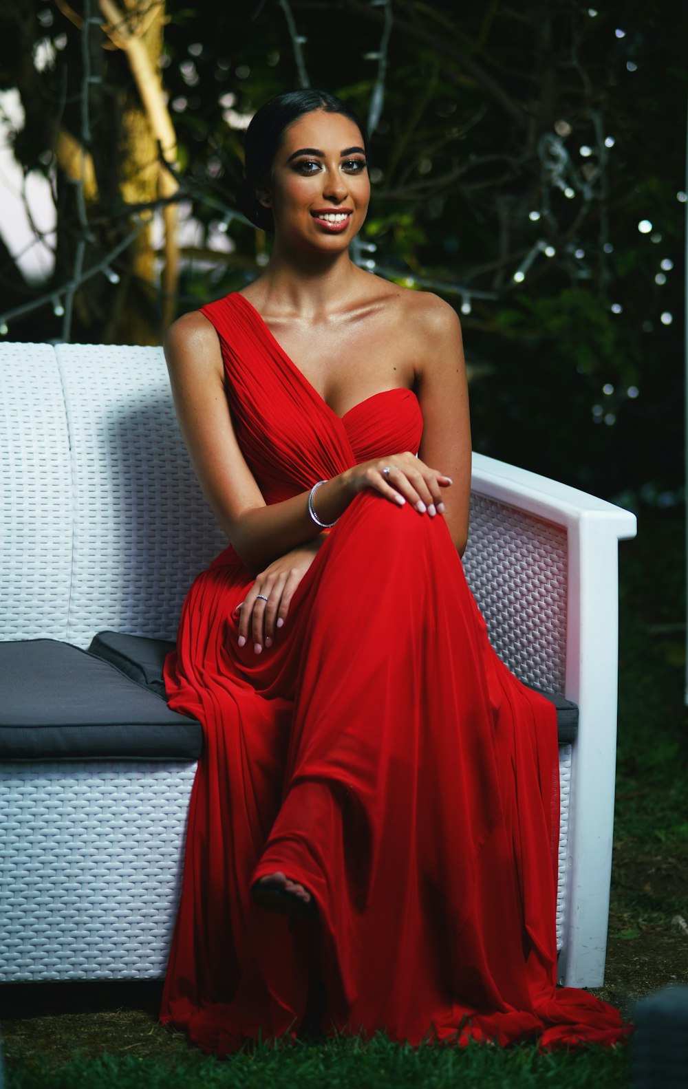 woman in red spaghetti strap dress sitting on white wooden bench